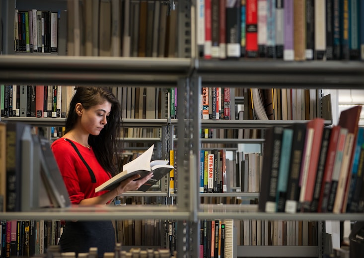 Woman studying in a library as she works to earn her online MBA