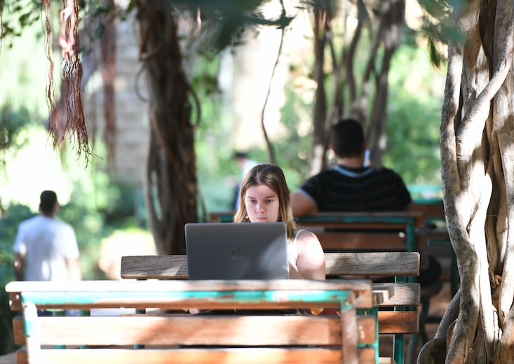 woman with laptop at park bench