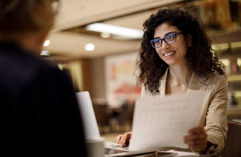 business analytics student handing paper to classmate