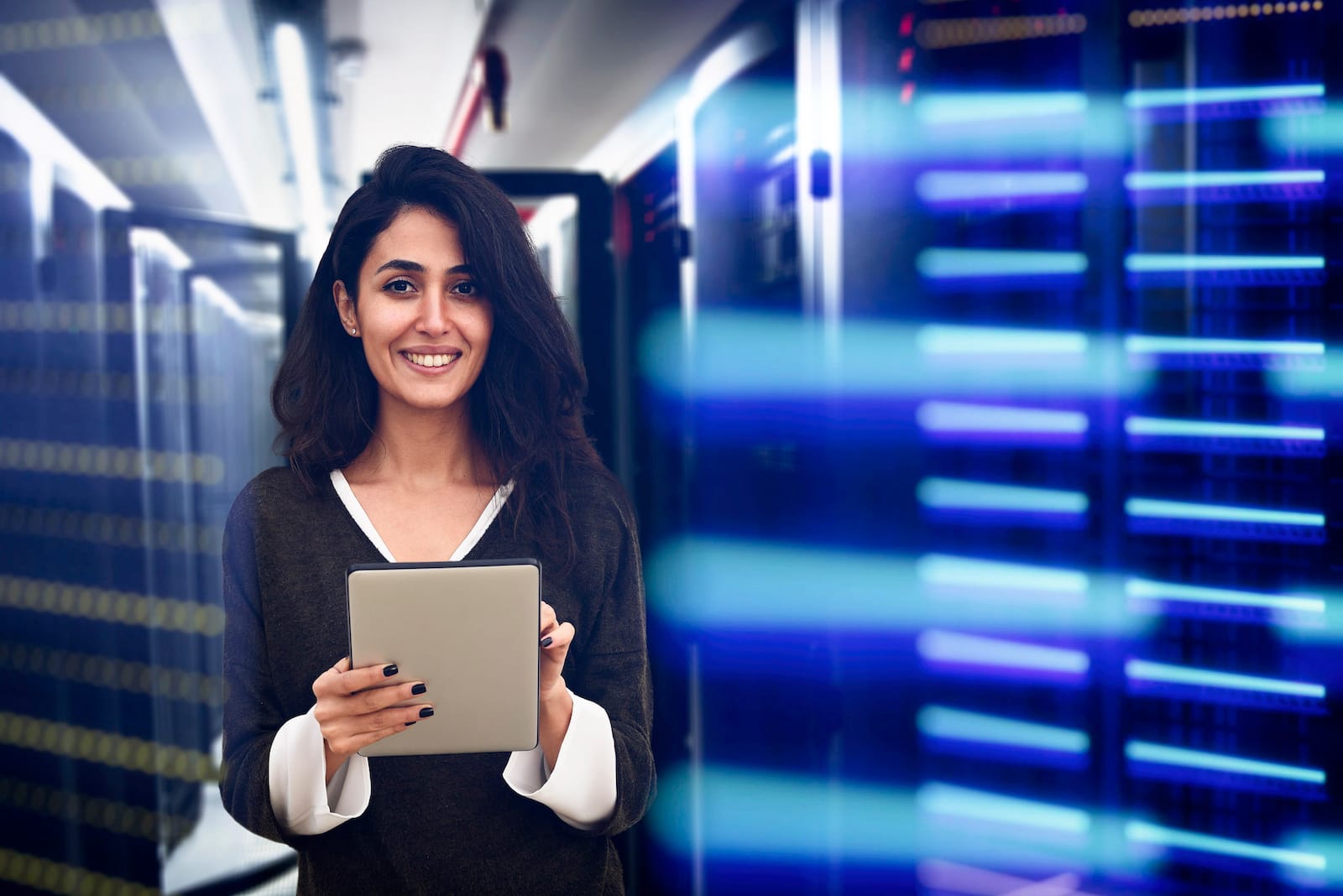 woman holding tablet in room of server racks